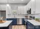 Modern kitchen boasts white cabinets, navy blue island and countertops, stainless steel appliances and ample natural light at 105 S York St, Lancaster, SC 29720