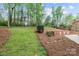 Spacious backyard with a brick retaining wall, mature trees, and well-maintained landscaping at 109 Stirling Heights Ln, Fort Mill, SC 29715