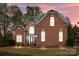 Beautiful brick and stone home with a manicured lawn and lush landscaping is bathed in the warm glow of the sunset at 109 Stirling Heights Ln, Fort Mill, SC 29715