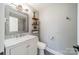 Compact bathroom featuring a vanity with marble countertop and stylish shelving for added storage at 1310 Seneca Pl, Charlotte, NC 28209