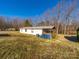 Rear view of home with a metal roof, wooden deck, and an expansive lawn on a sunny day at 137 Beaverbrook Rd, Statesville, NC 28677