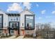 Modern townhome exterior with brick accents, a small porch, and a vibrant orange front door at 2132 Electric Ln, Charlotte, NC 28205