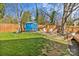 Fenced backyard featuring a charming blue storage shed, manicured lawn and a stone patio with comfortable white chairs at 2911 N Myers St, Charlotte, NC 28205