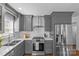 Modern kitchen featuring stainless steel appliances, gray cabinets, white subway tile backsplash, and a stainless steel range hood at 2911 N Myers St, Charlotte, NC 28205