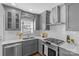 Well-lit kitchen with gray cabinetry, stainless steel appliances, stylish backsplash, and ample counter space at 2911 N Myers St, Charlotte, NC 28205