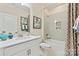 Bright bathroom with a white vanity, neutral paint, decorative tile shower, and framed botanical wall art at 407 Sunharvest Ln, Indian Trail, NC 28079