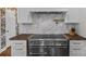 Close-up of range with stainless steel oven, wood countertops, and white cabinets at 4300 Denbigh Dr, Charlotte, NC 28226