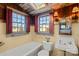 Vintage-style bathroom featuring a classic sink, tub, and window with red shutters, a bright and airy space at 4928 Tuckaseegee Rd, Charlotte, NC 28208