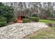 Charming backyard featuring a stone patio, lush greenery, and a rustic wooden deck with privacy screen at 5672 Wrenfield Ct, Charlotte, NC 28277