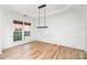 Elegant dining room with tray ceiling, hardwood floors, and stylish chandelier, perfect for entertaining at 5672 Wrenfield Ct, Charlotte, NC 28277