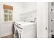 Functional laundry room with modern washer and dryer, window with modern blinds, and convenient shelving at 5672 Wrenfield Ct, Charlotte, NC 28277