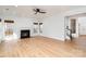 Bright living room boasting hardwood floors, a cozy fireplace, modern ceiling fan, and large windows at 5672 Wrenfield Ct, Charlotte, NC 28277