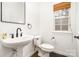 A simple powder room design featuring a pedestal sink and a modern black framed mirror at 5672 Wrenfield Ct, Charlotte, NC 28277