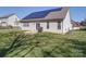 Backyard with solar panels, sliding glass doors, and a well-maintained lawn at 572 Church St, Locust, NC 28097