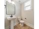 Well-lit powder room featuring pedestal sink, modern fixtures, and wood-look flooring at 574 Reid St, Belmont, NC 28012