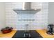 The kitchen boasts a stainless steel vent hood, subway tile backsplash and cooktop at 881 Saluda Rd, Chester, SC 29706
