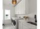 Well-lit laundry room with modern washer and dryer, white cabinets, and a sink with black faucet at 904 Van Every St, Charlotte, NC 28205