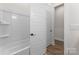 The well-lit bathroom features a pristine white tub and shower combo, complemented by a clean white door and neutral flooring at 12202 Anne Blount Aly, Davidson, NC 28036