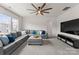 Spacious living room with a gray sectional sofa, ceiling fan, large windows, and a modern entertainment center with a large TV at 12202 Anne Blount Aly, Davidson, NC 28036