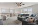 This expansive living room showcases a gray sectional sofa, ceiling fan, large windows, and elegant banister at 12202 Anne Blount Aly, Davidson, NC 28036