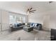 Bright living room featuring a large gray sectional, plush carpet, ceiling fan and ample natural light from the windows at 12202 Anne Blount Aly, Davidson, NC 28036