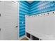The mudroom showcases stylish blue wallpaper, white cabinets and coat rack, and practical storage baskets for organization at 12202 Anne Blount Aly, Davidson, NC 28036