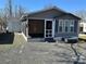Cozy home with gray siding, a screened porch, an adjacent garage, and a gravel driveway at 134 Cardinal Ave, New London, NC 28127