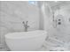 Bright bathroom featuring a soaking tub, walk-in glass shower, and marble tiling at 14314 Lissadell Cir, Charlotte, NC 28277