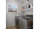 Efficient laundry room with modern washer and dryer, window, and storage shelves at 14723 Sapphire Ln, Pineville, NC 28134