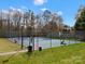 Outdoor tennis court with a basketball hoop, benches, and surrounding trees for recreational activities at 14723 Sapphire Ln, Pineville, NC 28134