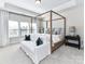 Bright bedroom featuring a four-poster bed, white sofa, and large windows at 15140 Rocky Bluff Loop, Davidson, NC 28036