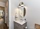Stylish powder room features a designer vanity with marble countertop, oval mirror and sconce lighting at 15140 Rocky Bluff Loop, Davidson, NC 28036