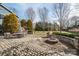 Landscaped backyard featuring a fire pit, stone wall, dining, and mature trees at 1740 12Th Street Nw Dr, Hickory, NC 28601