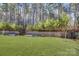Landscaped backyard featuring a retaining wall with metal planters and a private wooded backdrop at 17609 Caddy Ct, Charlotte, NC 28278