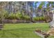 Spacious backyard featuring a retaining wall with metal planters and a wooded backdrop at 17609 Caddy Ct, Charlotte, NC 28278