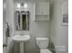 Compact half-bathroom with a pedestal sink, toilet, vanity mirror, and a neutrally painted wall at 17609 Caddy Ct, Charlotte, NC 28278