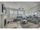 Open-concept living area with gray leather furniture, fireplace, large windows, and hardwood flooring at 17609 Caddy Ct, Charlotte, NC 28278