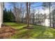 Grassy backyard with trees and a black metal fence leading to a lake at 208 Woodwinds Dr, Mount Holly, NC 28120