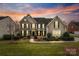 Beautiful two-story home with manicured lawn and lush landscaping at sunset at 208 Woodwinds Dr, Mount Holly, NC 28120