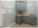 Neutral laundry room with shaker cabinets, tile floors, sink, and a window at 208 Woodwinds Dr, Mount Holly, NC 28120