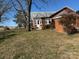 Rear exterior view of a brick home with a well-manicured lawn and a peaceful, rural setting at 3423 Crowder Ridge Rd, Shelby, NC 28150