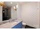 Unique bathroom features patterned wallpaper, starburst lighting and blue vanity at 4018 St Germaine Ln, Charlotte, NC 28210