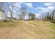 Wide view of the grassy backyard featuring mature trees surrounding a home with a bright, sunny sky at 422 Lee Ave, Wadesboro, NC 28170