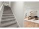 A well-lit living room featuring a carpeted stairway, and a hardwood floor with a modern sofa and neutral decor at 4890 Rio De Luna None, Hickory, NC 28601