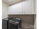 Modern laundry room with front load washer and dryer and white overhead cabinets at 503 Dixter Ln, Charlotte, NC 28211
