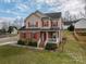 Inviting two-story home boasting a brick facade, red shutters, and a charming front porch at 5032 Meadow Woods Dr, Lowell, NC 28098