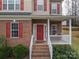 Close-up of the front entrance, highlighting the red door, brick facade, and welcoming porch with white railings at 5032 Meadow Woods Dr, Lowell, NC 28098