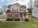 Charming two-story home featuring red shutters, brick accents, covered porch, and well-maintained landscaping at 5032 Meadow Woods Dr, Lowell, NC 28098