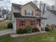 Two-story home showcasing a combination of brick and siding, complemented by vibrant red shutters and a well-kept lawn at 5032 Meadow Woods Dr, Lowell, NC 28098