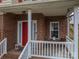 Cozy front porch with brick flooring, white railings, and a charming seating area, creating an inviting entrance at 5032 Meadow Woods Dr, Lowell, NC 28098